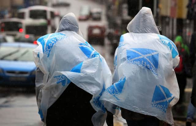 Tourists take cover in Edinburgh as heavy rain and storms hit Scotland. Picture: PA
