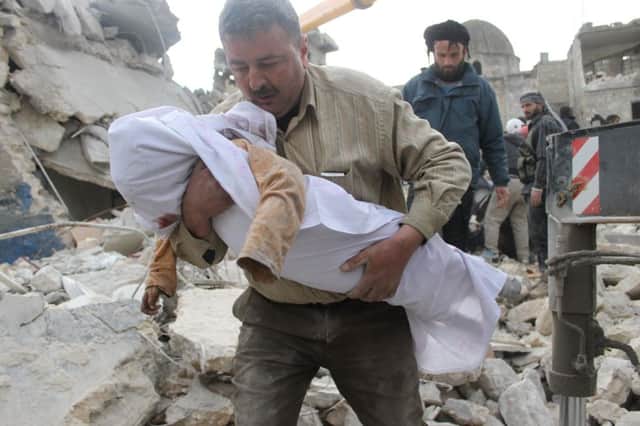 A man carries a childs body in Aleppo yesterday after alleged air raids by government forces. Picture: Getty