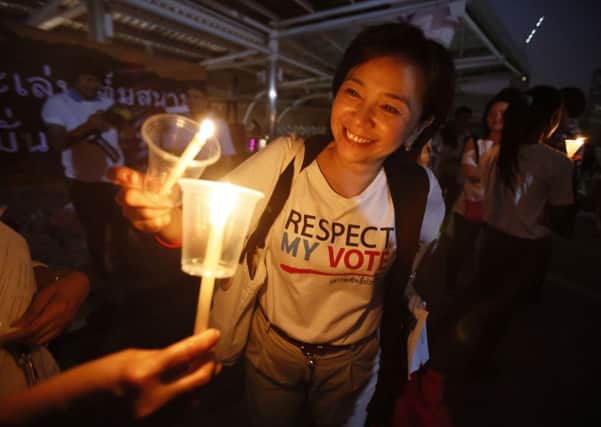A government supporter lights a candle during a vigil in Bangkok. Picture: AP
