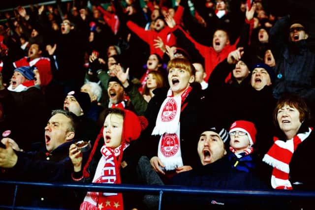 One young fan almost loses her pie as Aberdeen fans show their emotions during a match. Picture: Stuart Roy Clarke