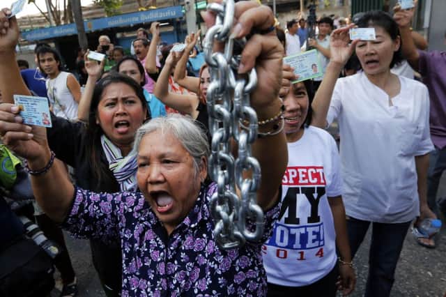 A woman holds up a chain that protesters had used to try to prevent people voting. Picture: Reuters