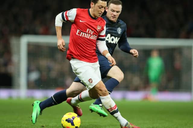 Arsenals Mesut Ozil, left, shields the ball from Manchester Uniteds Wayne Rooney. Picture: AP