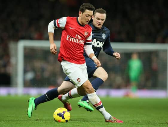 Arsenals Mesut Ozil, left, shields the ball from Manchester Uniteds Wayne Rooney. Picture: AP