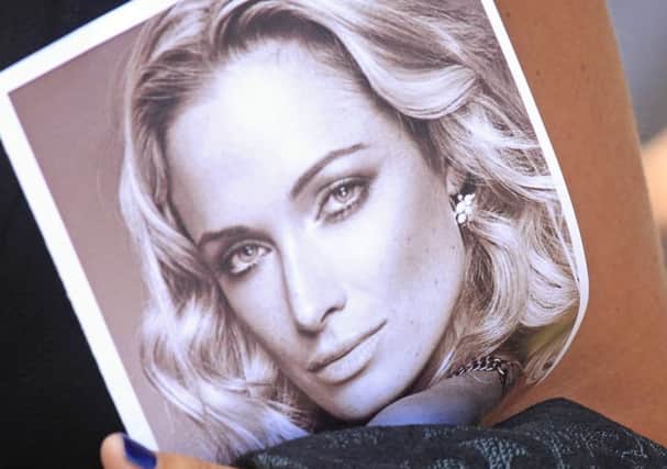 A woman holds a photo of Reeva Steenkamp as she leaves her funeral in Port Elizabeth, South Africa. Picture: AP