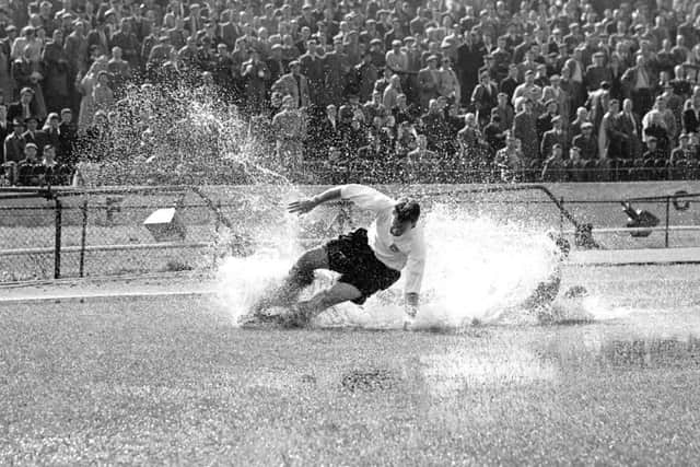 Preston North End's Tom Finney splashes through a puddle in a match in 1956. Picture: PA