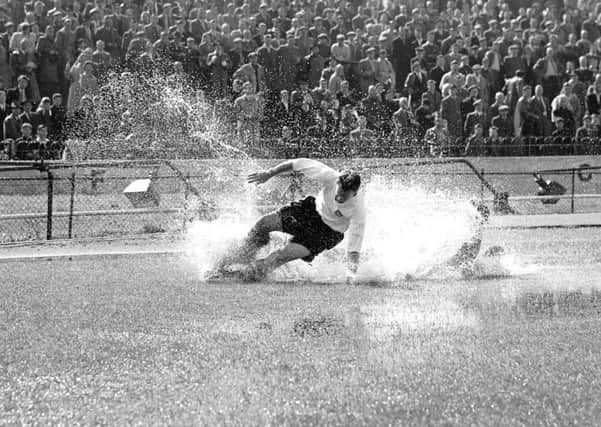 Preston North End's Tom Finney splashes through a puddle in a match in 1956. Picture: PA