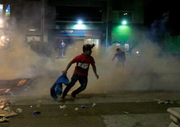 Demonstrators in Caracas run for cover as police fire tear gas. Two students were shot in different incidents. Photograph: Alejandro Cegarra/AP