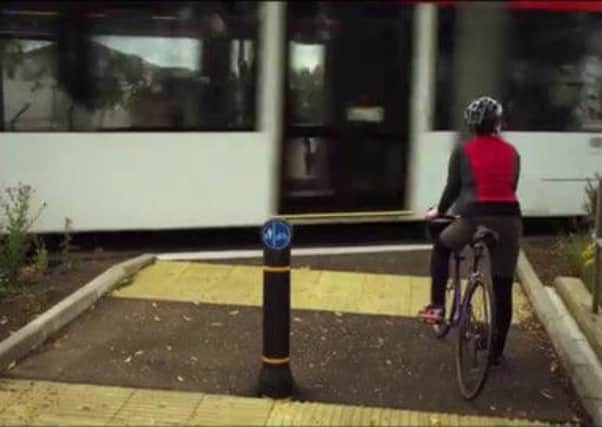 A cyclist waits for a tram to pass in a still from the video. Picture: Contributed