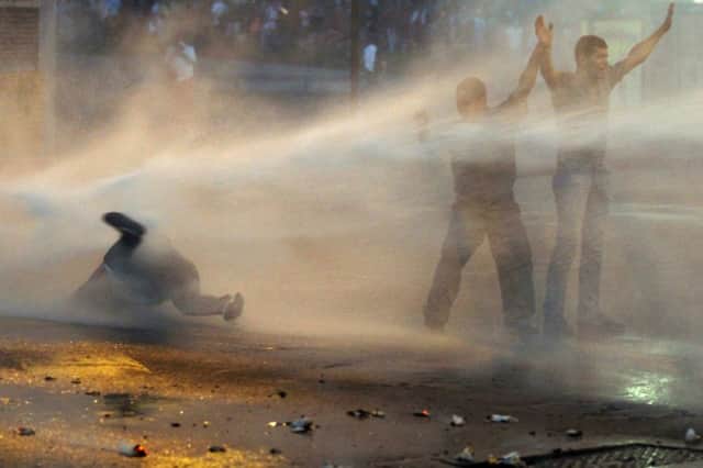 Leopoldo Lopez supporters are hit by a police water cannon in Caracas. Picture: Reuters
