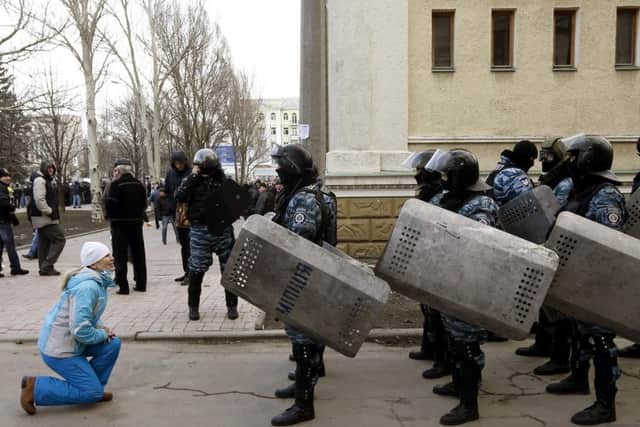 A woman kneels in front of Ukranian riot police. Picture: Reuters