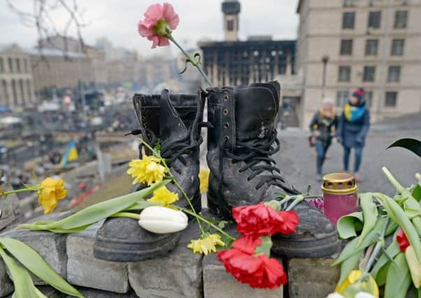 A pair of boots strewn with flowers serves as a shrine to one of the protesters killed. Picture: Jeff J Mitchell