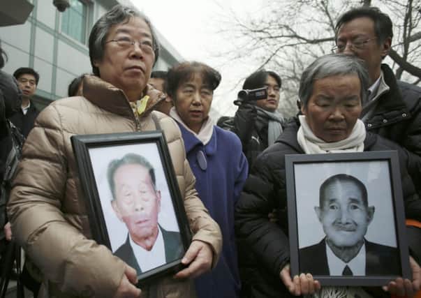 Relatives hold portraits of Chinese victims of forced labour during World War Two. Picture: REUTERS/China Daily