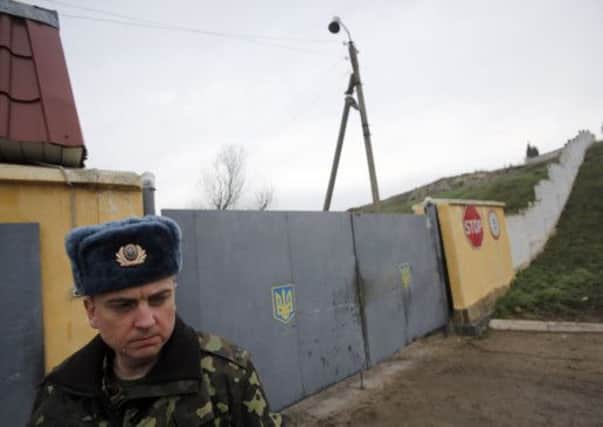 A Ukrainian officer stands outside the gate of a military base at the Black Sea port of Sevastopol. Picture: AP