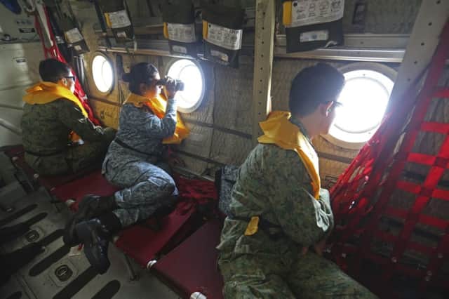 Military personnel look out of a Republic of Singapore Air Force (RSAF) C130 transport plane as they search for the missing Malaysia Airlines MH370 plane over the South China Sea. Picture: Reuters