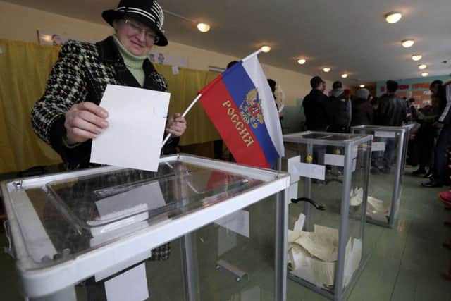 A woman with a Russian flag casts her ballot in Crimea. Picture: Reuters