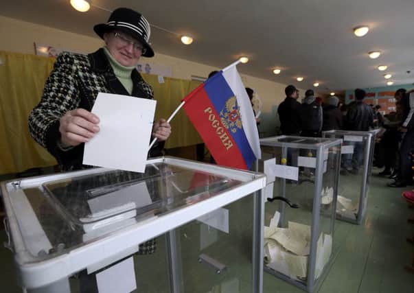 A woman with a Russian flag casts her ballot in Crimea. Picture: Reuters