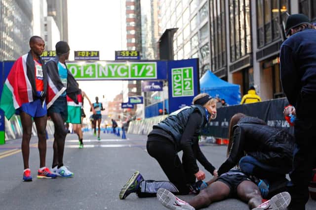 Collapsed at the finish line, wife and race officials attend to Mo Farah. Picture: Getty