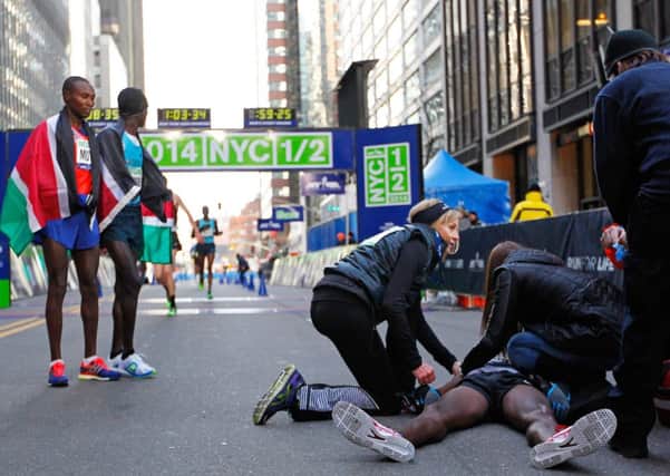 Collapsed at the finish line, wife and race officials attend to Mo Farah. Picture: Getty