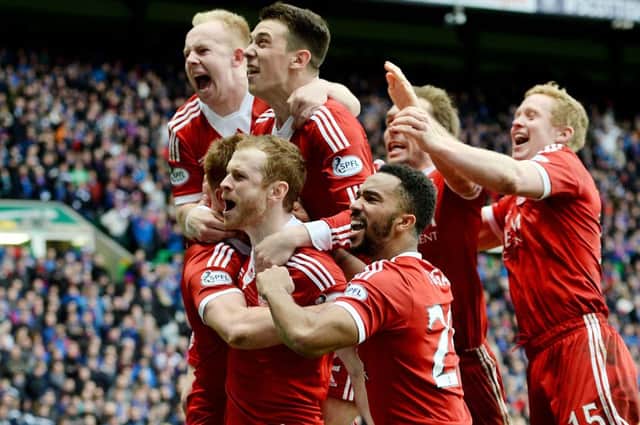 Adam Rooney is engulfed by his jubilant Aberdeen team-mates after netting the decisive penalty. Picture: SNS
