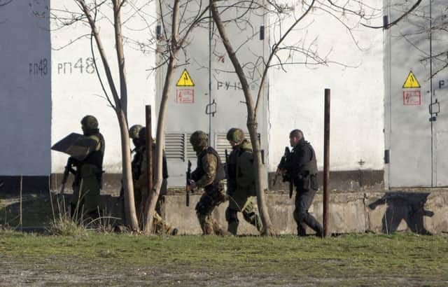 Unidentified armed men search an area close to an Ukrainian military unit in Crimea. Picture: AP