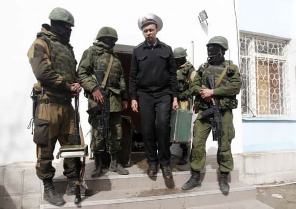 Masked Russianspeaking militiamen conduct a Ukrainian naval officer from the Sevastopol base. Picture: Reuters