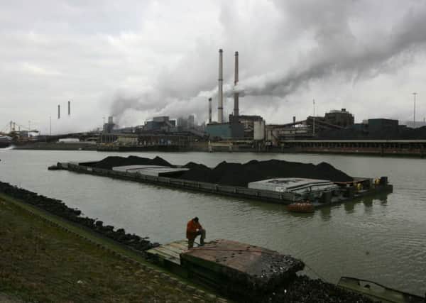 A worker is seen on a pontoon near Corus steelmaker, owned by Tata Steel Lrd, rear, in Ijmuiden, Netherlands. Picture: AP