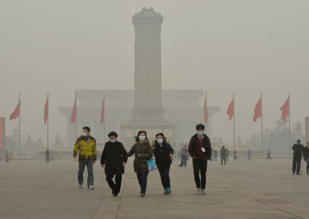 Chinese tourists wear facemasks during a visit to Tiananmen Square. Picture: Getty