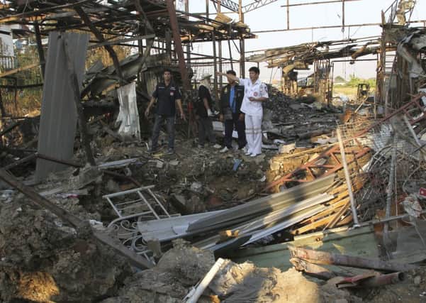 Thai charity workers stand next to a crater created by a bomb explosion at a scrap shop in Bangkok, Thailand. Picture: AP