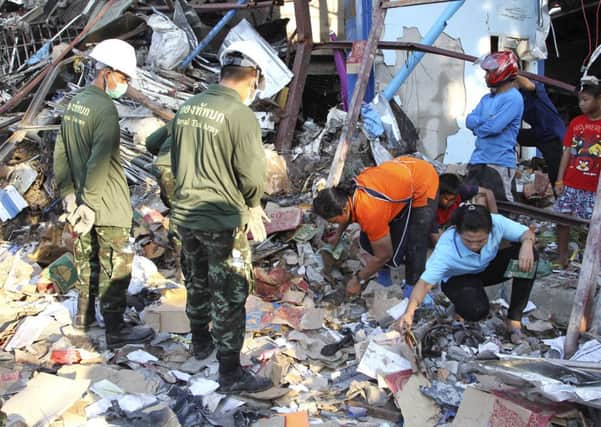 Residents, right, sift through the wreckage of a scrap shop as Thai soldiers, left, watch after a bomb explosion in Bangkok, Thailand. Picture: AP