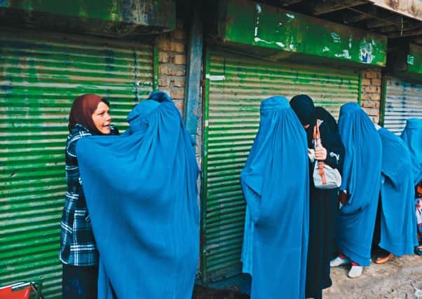 An Afghan official frisks female voters waiting to enter a polling station in Kabul. Picture: Getty