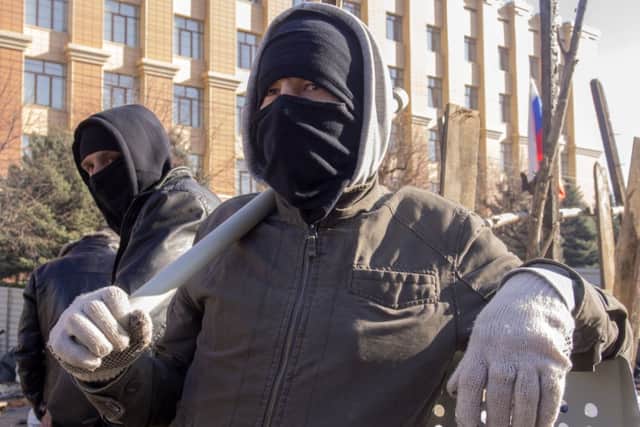 Pro-Russian activists in face masks stand near a barricade in front of an entrance of the Ukrainian regional office of the Security Service in Luhansk,  a crowd of pro-Russian activists later stormed the building on Sunday. Picture: AP