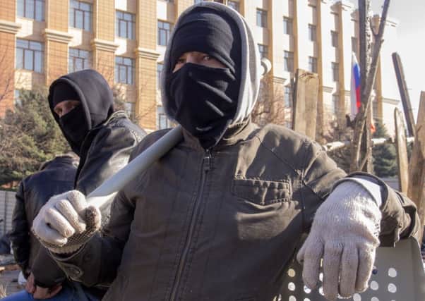 Pro-Russian activists in face masks stand near a barricade in front of an entrance of the Ukrainian regional office of the Security Service in Luhansk,  a crowd of pro-Russian activists later stormed the building on Sunday. Picture: AP