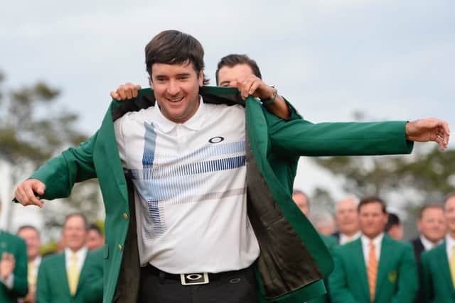 Last years champion, Adam Scott, helps Bubba Watson slip on the Green Jacket. Picture: Getty