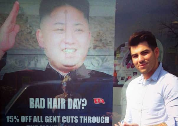 Barber Karim Nabbach standing next to the offending poster. Picture: AP