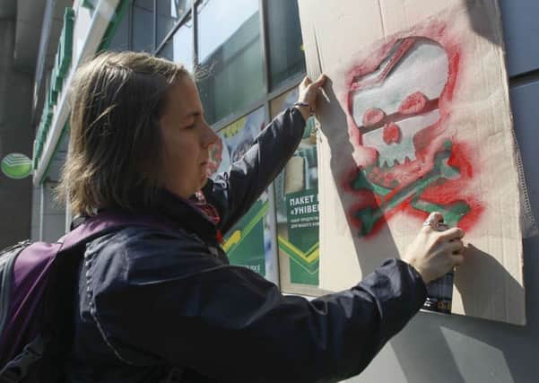 An activist paints graffiti outside a regional branch of Sberbank, Russia's largest bank, during a protest in Kiev. Picture: Reuters