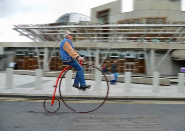 Norman Mayer rides a 1885 Penny Farthing past the Scottish Parliament. Picture: Jon Savage