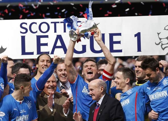 Surrounded by his jubilant teammates, Rangers captain Lee McCulloch lifts the Scottish League One trophy at Ibrox. Picture: Reuters