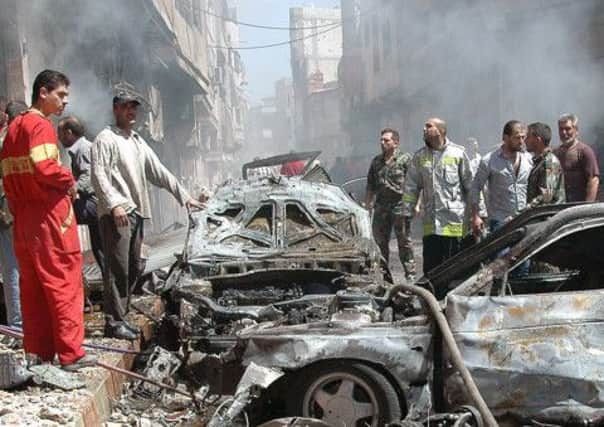 Emergency personnel and locals check out the site of the car bomb in Homs. Picture: AFP/Getty Images