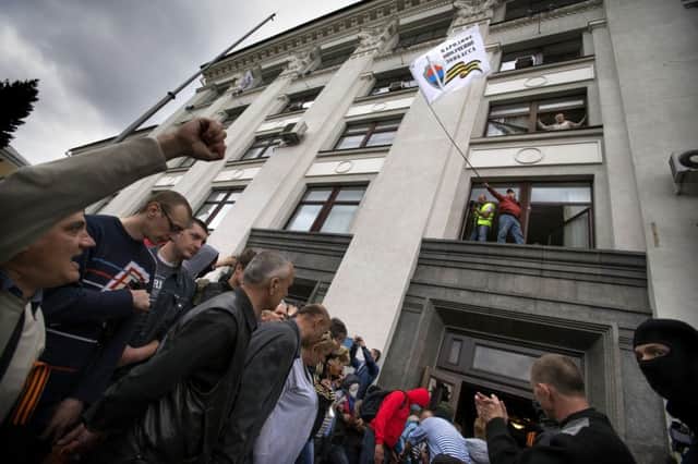 A proRussian activist waves a flag over a crowd celebrating the capture of a building in Luhansk. Picture: AP