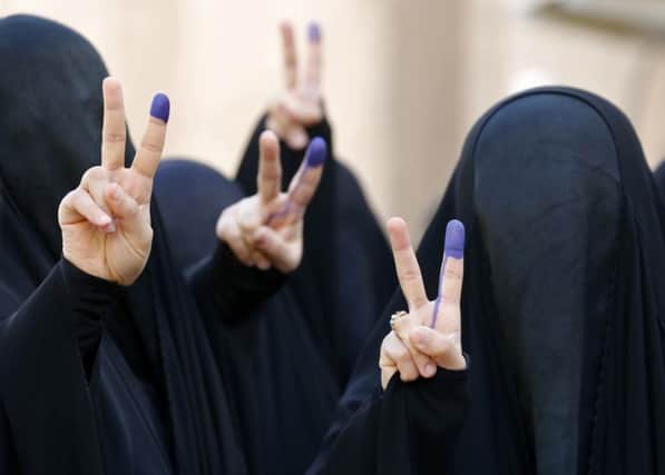 Women voters in Baghdads Karradah district. Left: Polling station guard in Najaf. Picture: Getty