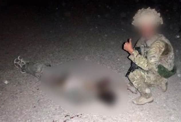 This photograph appears to show an RAF gunner giving a thumbs-up sign, next to the body of a dead insurgent. Picture: Contributed