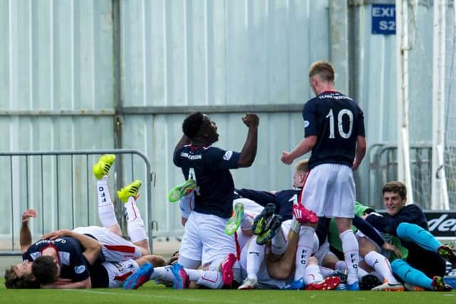 Falkirk players dive on top of Blair Alston after he scored the winning goal against Queen of the South in extra-time. Picture: SNS Group