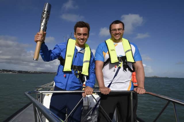 Tom Daley and Team Jersey shot-putter Zane Duquemin with the baton. Picture: PA
