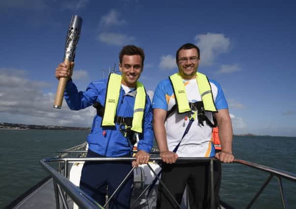 Tom Daley and Team Jersey shot-putter Zane Duquemin with the baton. Picture: PA