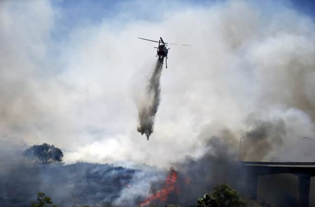 Water is dropped from a helicopter in a bid to tackle the wildfire raging in and around San Diego, California. Picture: AP