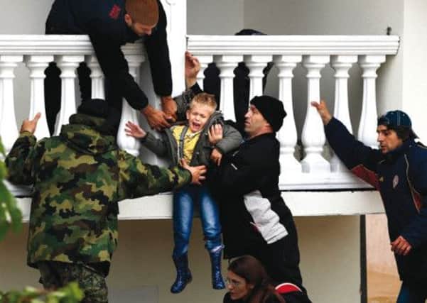 Serbian soldiers evacuate a boy from a house in the town of Obrenova. Picture: Marko Djurica