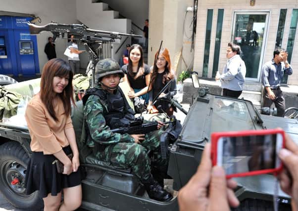 Passersby pose for a photo with Thai army soldiers on guard in central Bangkok after martial law was declared. Picture: Getty