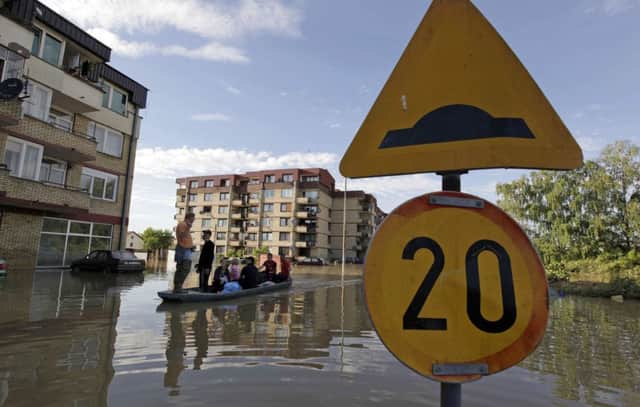 Locals in Samac negotiate the flooded town in a boat. The waters is receding, but many problems remain. Picture: Reuters