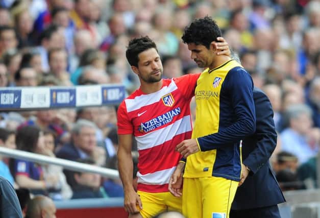 Diego Costa is consoled by Atletico teammate Diego Ribas following his injury during the draw with Barcelona. Picture: Manu Fernandez/AP