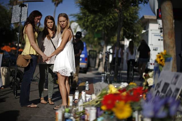 Amber McCoy, 20, Ava Ames, 23, and Jenn Bowman, 21, in front of a makeshift memorial in Isla Vista. Picture: Reuters